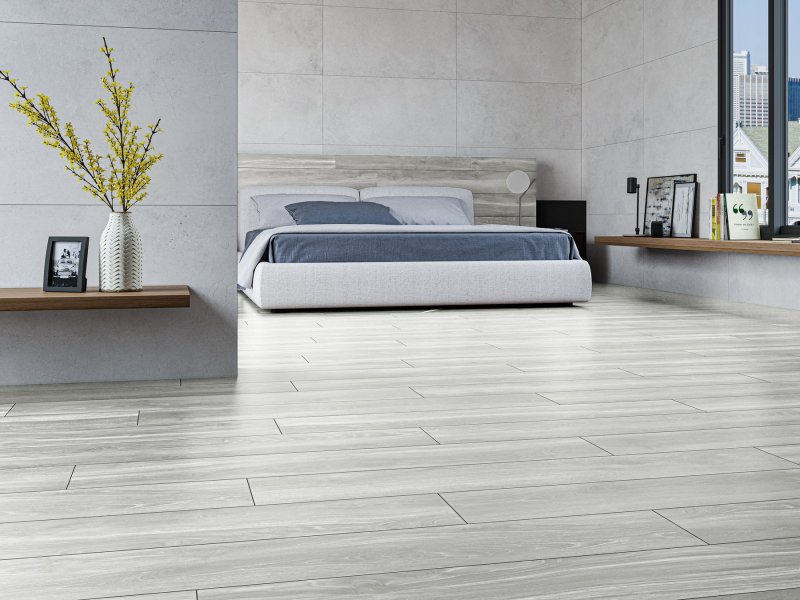 Slaapkamer met lichte Helsinki Perla-vloer, grijs beddengoed en lichte wanden.
